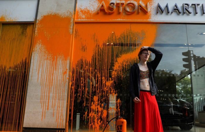 Environmental activists have sprayed paint on the window of an Aston Martin showroom in London.